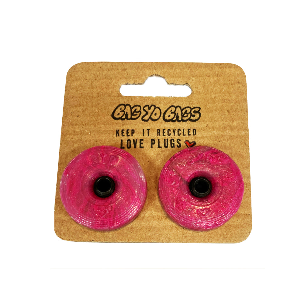 Bag Yo Bags Bar Ends Pink Add some eco-friendly flair to your ride with Bag Yo Bags Bar Ends! Made from recycled bags in Québec, these bar ends are not only strong, but also a statement piece for the environmentally conscious rider. Upgrade your mount with a touch of sustainability today!
