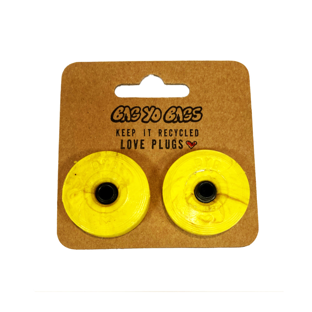 Bag Yo Bags Bar Ends Yellow Add some eco-friendly flair to your ride with Bag Yo Bags Bar Ends! Made from recycled bags in Québec, these bar ends are not only strong, but also a statement piece for the environmentally conscious rider. Upgrade your mount with a touch of sustainability today!